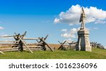 A stone monument of a civil war soldier stands before a wooden split rail fence as it marks the location of Antietam National Battlefield in Sharpsburg, Maryland