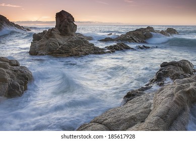 stone on seashore at sunset with a wave