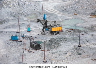 Stone Open Pit. Excavator Is Loading Raw Materials Into Yellow Truck For Transport To Combine.