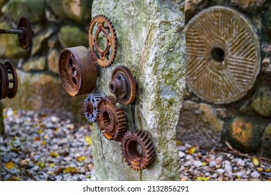 A stone in the park is inlaid with a pile of rusty gear sculptures - Shutterstock ID 2132856291