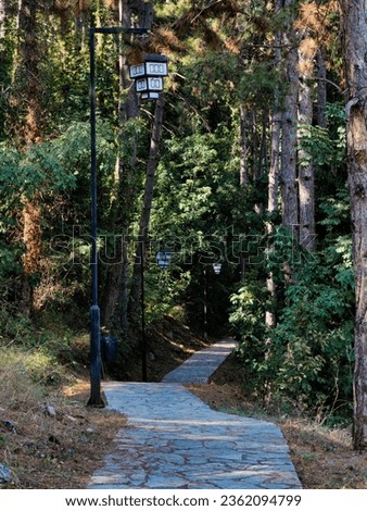 Stone path, hiking track to the forest. Black poles , street lanterns decoration shape model old macedonian traditional house. during day. Light and shadow. Ohrid city, Macedonia 2023.