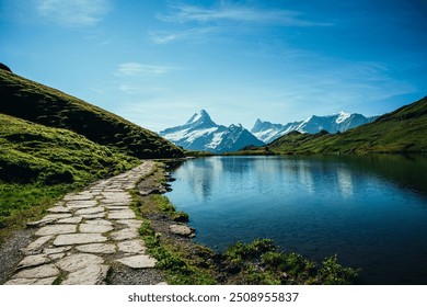 Stone pathway beside swiss alpine lake with mountains in distance - Powered by Shutterstock