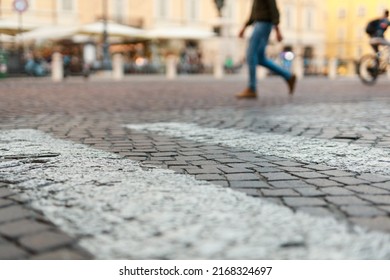 Stone Pavement In Perspective. Old Street Paved With Stone Blocks With White Lines. Shallow Depth Of Field. Vintage Grunge Texture. City ​​and People On Background.