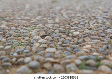 Stone Pavement In Perspective. Old Street Paved With Stone Blocks With White Lines. Shallow Depth Of Field. Vintage Grunge Texture. City ​​and People On Background.