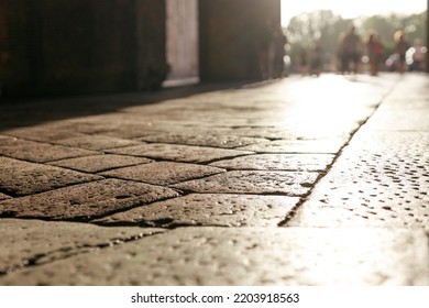 Stone Pavement In Perspective. Old Street Paved With Stone Blocks With White Lines. Shallow Depth Of Field. Vintage Grunge Texture. City ​​and People On Background.