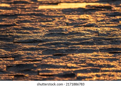 Stone pavement in the rays of the setting sun. Backround of Block pavement on sunset. Texture