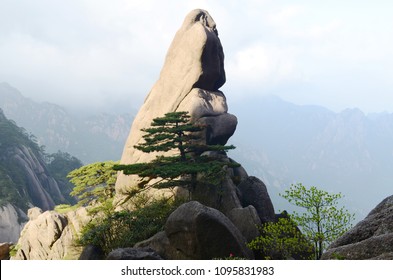 Stone peaks at the Yellow Mountain, China. With low hanging clouds and green trees.