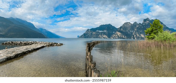 Stone pier in lakeside town Nago-Torbole, Lake Garda, Trentino, Italy. Seagull birds sitting on wooden poles on Lake Garda. Surrounded by steep rugged mountains of Garda Prealps. Wildlife watching - Powered by Shutterstock