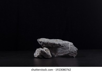 Stone podium for showing packaging and product on dark black background, copy space.