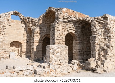 Stone ruins of ancient buildings on the Acropolis of Lindos, Greece. These historic remnants offer a glimpse into the architectural legacy of the ancient Greek civilization. - Powered by Shutterstock