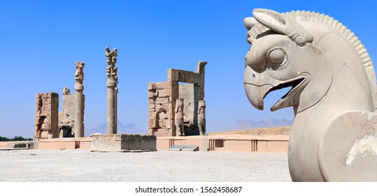 Stone Sculpture Of Griffin And Gate Of All Nations (Xerxes Gate) In The Ancient City Of Persepolis, Iran. UNESCO World Heritage Site. On Blue Sky Background