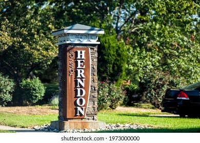 Stone sign for city or town of Herndon in Northern Virginia suburbs by green trees park near Washington DC