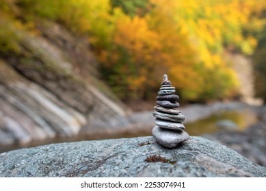Stone stack with balanced stones on blurred mountain background in sunset warm light in autumn foliage