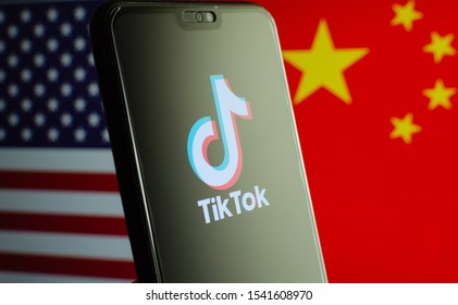 Stone, Staffordshire / UK - October 25 2019: TikTok app logo on a smartphone screen and flags of China and United States on the blurred background. The app is in centre of US - China tensions.