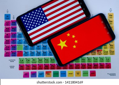 Stone, Staffordshire / United Kingdom - May 30 2019: Trade war. The photo of USA and China flags on Huawei smartphones which are laying on the periodic table around the groups of rare earth minerals. 
