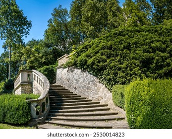 Stone staircase with an ornate railing and vibrant greenery in the Römischer Garten public park in Hamburg Blankenese, tranquility and charm, ideal for travel guides or landscaping inspiration. - Powered by Shutterstock