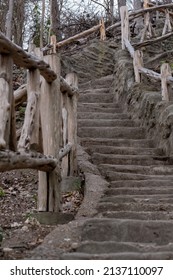 A Stone Staircase With A Wooden Railing Winding Up A Hill