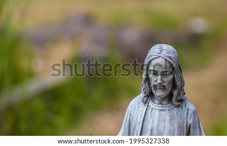A stone statue of jesus against a blurry background