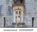 Stone statue of Saint Blaise above west entrance gate at protective city walls of Dubrovnik.