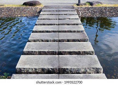 A stone step bridge over a small garden pond