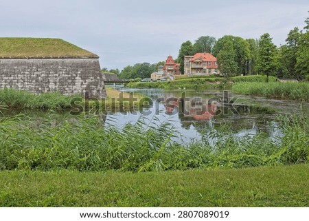 Stone structure on the left is part of the Kuressaarre castle's extensive fortification system, which includes bastions and walls surrounded by a moat and on the right are Ekesparre Boutique Hotel and Kuressaare Beach House in cloudy summer weather, Kuressaare, Saaremaa, Estonia, Europe.