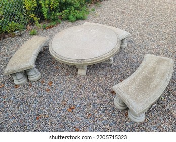 A Stone Table With Some Stone Benches Around It Sitting On Crushed Rock.