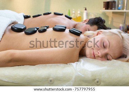 Stone therapy in spa salon. Relaxed young couple receiving hot stone therapy at beauty spa. Beautiful young couple enjoying hot stone therapy in spa centre.
