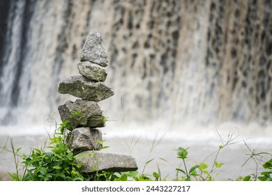 Stone tower on waterfall stream background. Rock Balancing or rock stacking hobby in the nature. Empty blank copy text space.