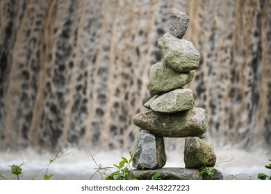 Stone tower on waterfall stream background. Rock Balancing or rock stacking hobby in the nature. Empty blank copy text space.