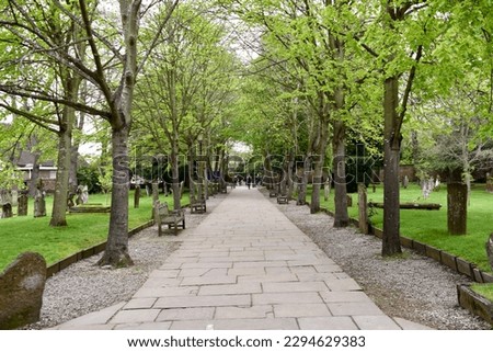 Stone tree lined footpath through a cemetary. Stratford-upon-Avon, UK. April 2023. 