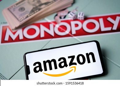 Stone, United Kingdom - December 17 2019: Amazon Logo On Smartphone Placed Next To Monopoly Game With Real Money. Conceptual Photo.