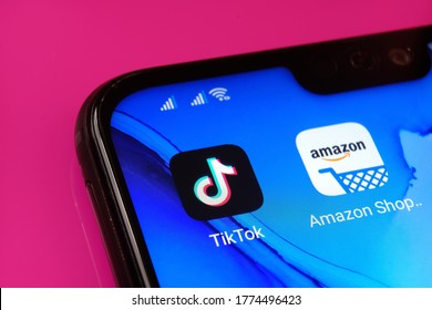 Stone / United Kingdom - July 11 2020: TikTok and Amazon apps seen on the corner of the smartphone placed on pink surface.