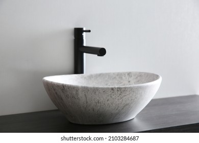 Stone vessel sink with faucet on wooden countertop
