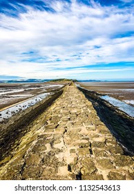The stone walkway linking the Edinburgh cost mainland to Cramond Island at low tide on a summer evening.
