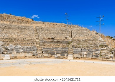 A stone wall with a stone archway and a stone staircase. The wall is on a hill and the sky is blue. Ruins of the ancient city of Philippi, Greece - Powered by Shutterstock