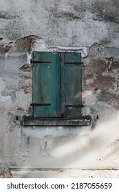 Stone Wall Cracked And Rough With Old Green Wooden Window , Shutters Closed, Shadow On The Wall, No Person