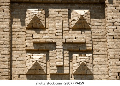 Stone wall features geometric brick pattern with triangular shapes. Sunlight highlights texture and depth of each brick. Symmetrical design creates bold, modern architectural impression