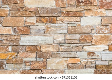 Stone wall of natural stones in different sizes; Rustic stone veneer in shades of brown and beige; Wall covering with natural stones