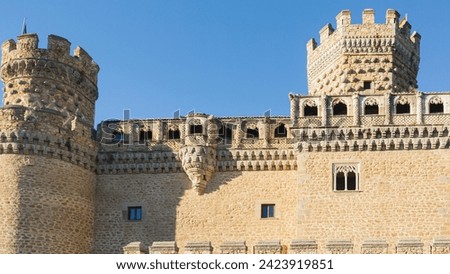 The stone wall of the old castle against the blue sky with two towers and arched windows. A historical landmark in the old town in Spain