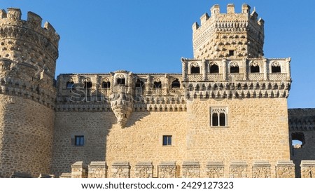 The stone wall of the old castle against the blue sky with two towers and arched windows. A historical landmark in the old town in Spain