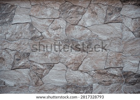Stone wall texture with irregular brown and gray slate tiles pattern.