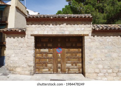 stone wall with a wooden garage door with a large parking prohibited sign