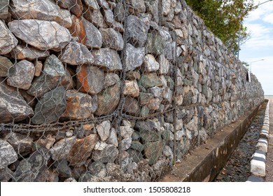 Stone walls for blocking the collapsing stone. Stone wall covered with a net. stone gabion wall.