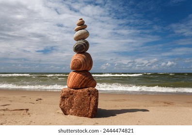 Stone zen pyramid made of colorful pebbles on the beach against a stormy sea. Concept of Life balance, harmony and meditation