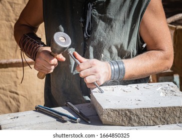 stonemason working with his tools, focused in the foreground with medieval attire