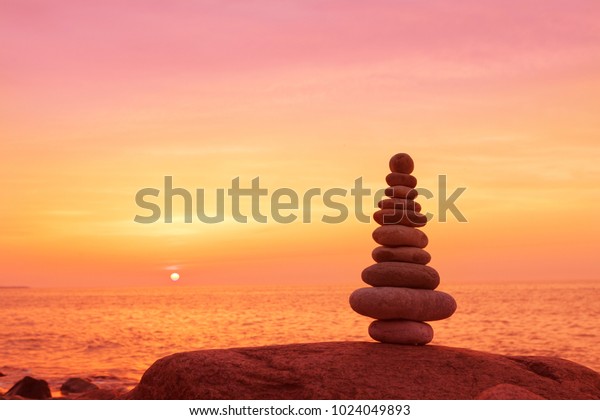 Stones balance on a background of\
sea sunset. Calm and meditation. Concept of harmony and\
balance