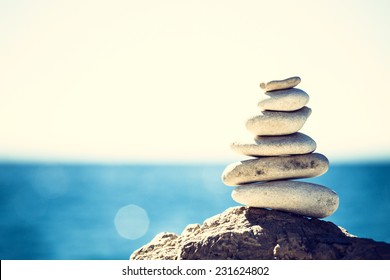 Stones Balance, Vintage Retro Instagram Like Hierarchy Stack Over Blue Sea Background. Spa Or Well-being, Freedom And Stability Concept On Rocks.