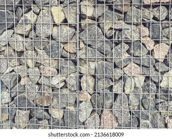 Stones In A Metal Mesh. A Mountain Of Gray, Voluminous, Structural Stones Lie In A Metal Structure As An Element Of Decor. DIY Fence For Home.