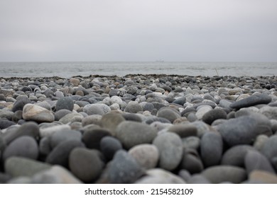 Stones On The Beach. Focus On The Middle Ground. Ship In The Background