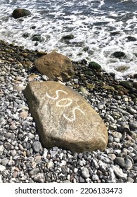 Stones On The Beach, Sos Sign Written On A Stone, Sea